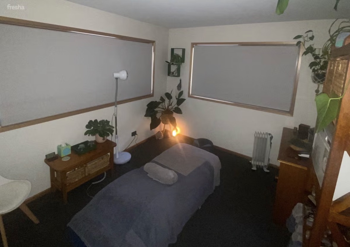 Warm, candle-lit treatment room with massage table, plants and salt lamp